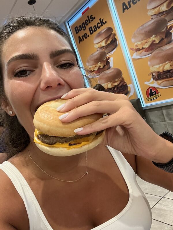 Alex biting into her McDonald's Steak, Egg & Cheese Bagel
